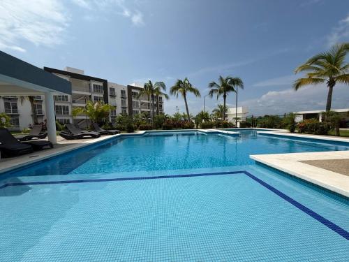 a large blue swimming pool with palm trees and buildings at Puerta al Sol in Acapulco
