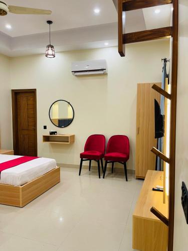 a bedroom with a bed and two red chairs at Hotel Karachi Guest House in Karachi