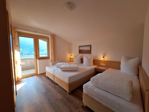 a hotel room with two beds and a window at Alpenzeit Zillertal Apartments in Zell am Ziller
