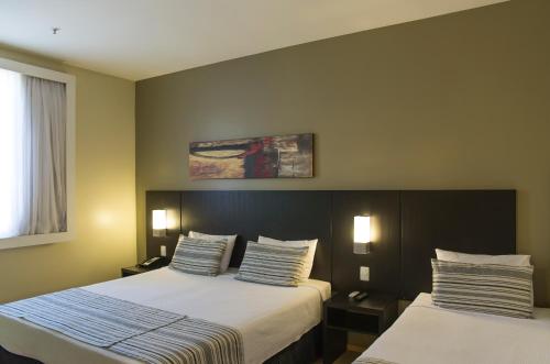 a hotel room with two beds and a window at Grande Hotel Petrópolis in Petrópolis