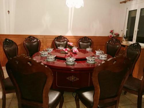 a dining room table with chairs and a red table with flowers on it at Rosen Garten Haus in Titisee-Neustadt
