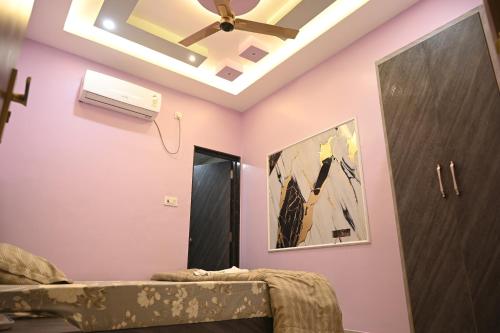 a bedroom with a ceiling fan and pink walls at Kashi Om Vilas Homestay in Varanasi