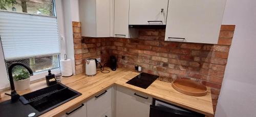 a kitchen with white cabinets and a wooden counter top at Apartamenty Nadmorskie lofty in Gąski