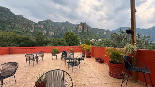 a patio with chairs and tables with mountains in the background at La Pirámide del Tepozteco in Tepoztlán