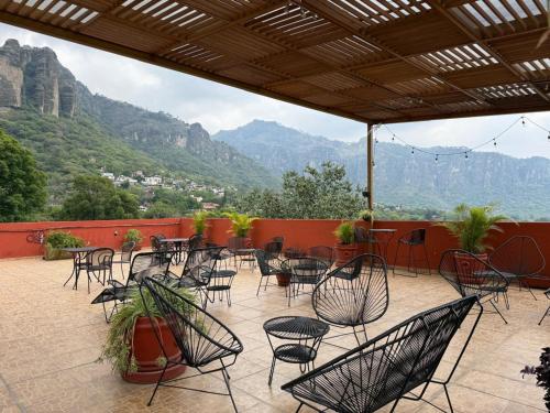a patio with chairs and tables with mountains in the background at La Pirámide del Tepozteco in Tepoztlán