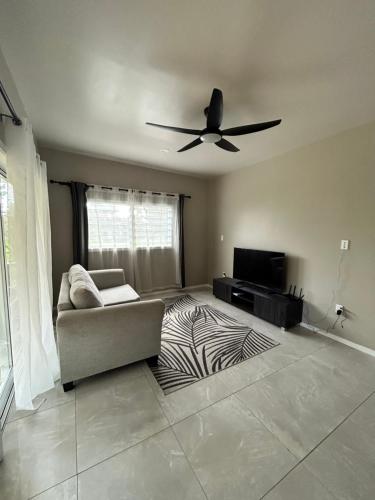 a living room with a couch and a ceiling fan at Are Tautu Villa in Avarua