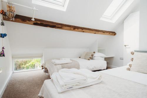 two beds in a room with white walls and windows at The Cow Byre in Dursley
