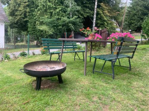two benches and a table with a grill and flowers at Chalupa U Pastvišť in Stachy