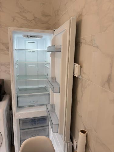 an empty refrigerator with its door open in a bathroom at Petite Maison Cosy Orly in Orly