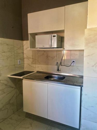 a small kitchen with a sink and a microwave at Apto compacto para familia in Fortaleza