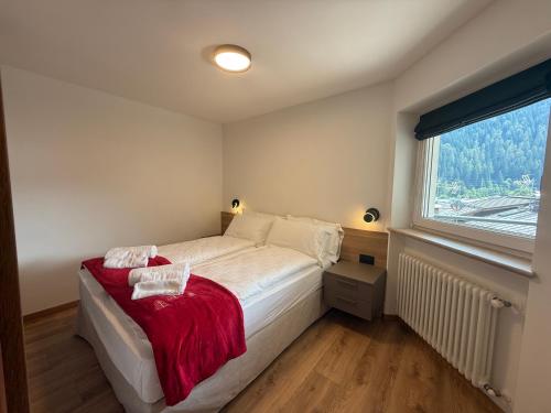 a bedroom with a bed with a red blanket and a window at Al Piz - Dimora Alpina in Pellizzano