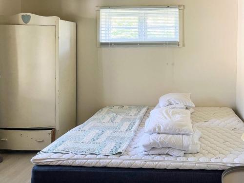 a small bedroom with a bed with a refrigerator at 6 person holiday home in Løkken in Løkken