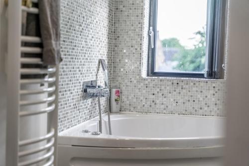 a bathroom with a sink and a bath tub with a window at Chingford Manor in Chingford
