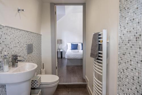 a bathroom with a sink and a toilet and a bedroom at Chingford Manor in Chingford