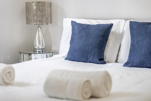a white bed with blue pillows and blue pillows at Chingford Manor in Chingford