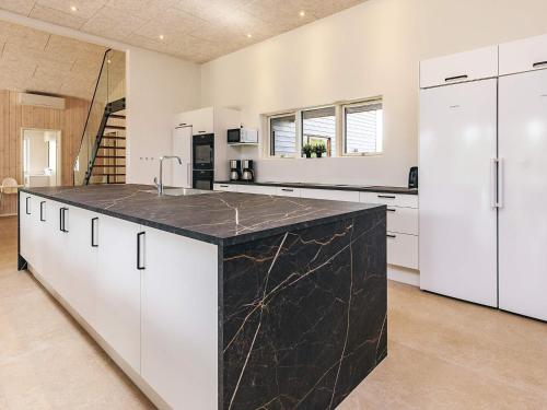 a large kitchen with white cabinets and a black counter top at 5 star holiday home in Højslev in Højslev