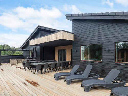 a deck with chairs and tables on a house at 5 star holiday home in Højslev in Højslev