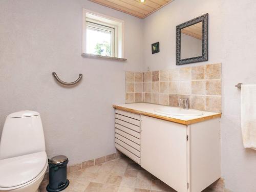 een badkamer met een toilet, een wastafel en een spiegel bij 6 person holiday home in Løgstør in Løgsted
