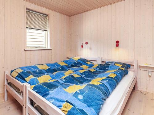 een slaapkamer met een bed met een blauwe en gele quilt bij 6 person holiday home in Løgstør in Løgsted
