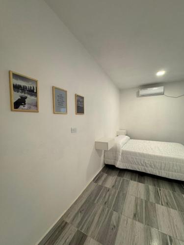 een witte kamer met een bed en foto's aan de muur bij Temporal Colonia Caroya in Colonia Caroya