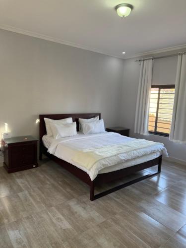 ein Schlafzimmer mit einem Bett mit weißen Laken und Kissen in der Unterkunft MY Home Apartments in Lusaka