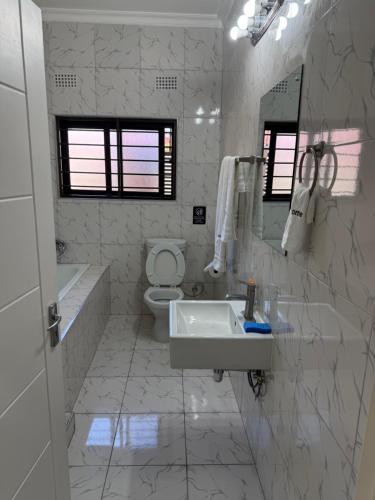 ein weißes Badezimmer mit Waschbecken und Toilette in der Unterkunft MY Home Apartments in Lusaka