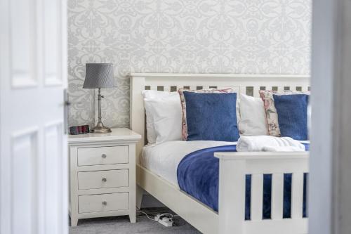 a bedroom with a bed with blue and white pillows at Chingford Manor in Chingford