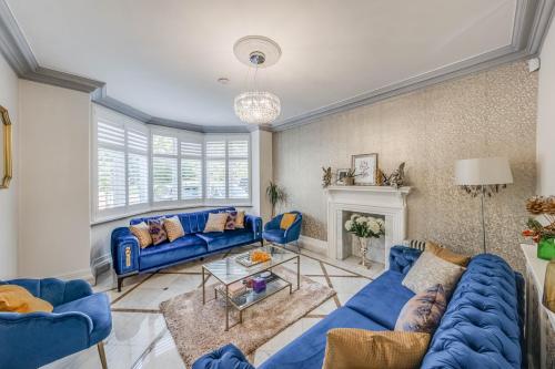 a living room with blue couches and a fireplace at Chingford Manor in Chingford