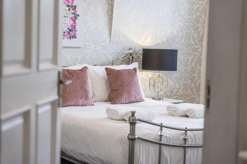 a bedroom with a bed with pink and white pillows at Chingford Manor in Chingford