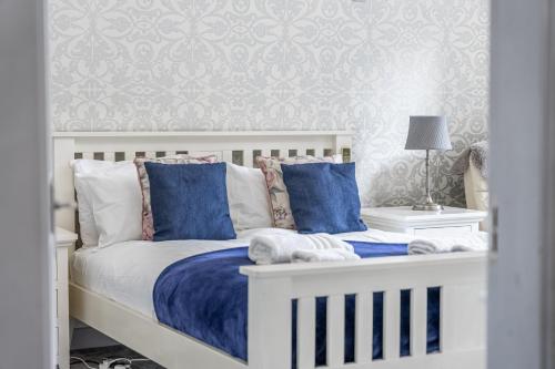 a bedroom with a white bed with blue pillows at Chingford Manor in Chingford