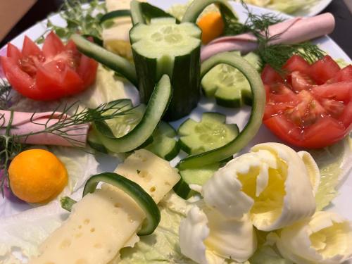 a plate of food with tomatoes cucumbers and vegetables at Bio-Nestlein Apartments in Löffingen