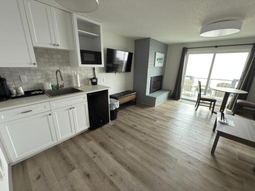 a kitchen with white cabinets and a dining room with a table at West Beach Suites in Lincoln City