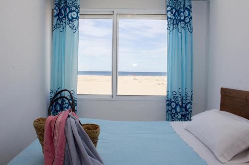 a bedroom with a bed and a view of the beach at Apartamentos Calypso in Punta Umbría