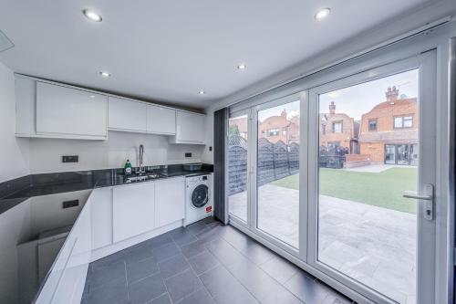 a kitchen with white cabinets and a large window at Chingford Manor in Chingford