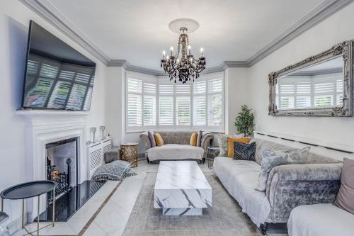 a living room with a fireplace and a chandelier at Chingford Manor in Chingford