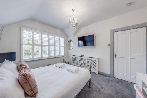 a white bedroom with a bed and a window at Chingford Manor in Chingford