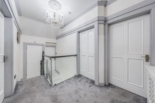 a hallway with white doors and a chandelier at Chingford Manor in Chingford