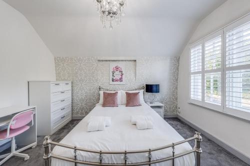 a white bedroom with a large bed with pink pillows at Chingford Manor in Chingford