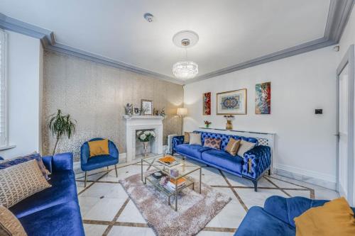 a living room with blue couches and a fireplace at Chingford Manor in Chingford