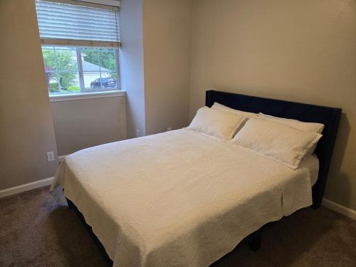 a bedroom with a bed with white sheets and a window at Spacious 5BR Walk to Wild Waves! in Federal Way