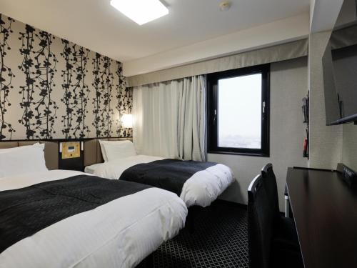 a hotel room with two beds and a window at APA Hotel Tonami Ekimae in Tonami