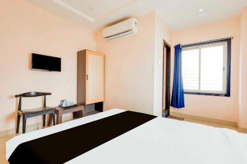 a bedroom with a bed and a window and a chair at Hotel O Kakinada near JNTU in Kākināda