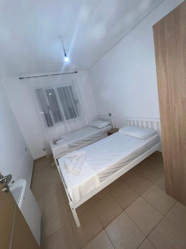 a white bedroom with two beds in a room at Vila Oron in Vlorë