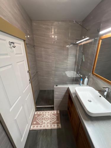 a bathroom with a sink and a white door at Grand Large - cosy studio in Papeete