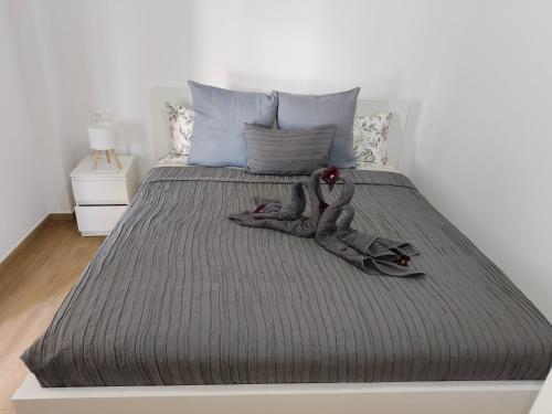 a bed with a gray comforter with a doll on it at Piedras del Teide in Guía de Isora