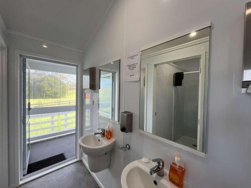 ein weißes Badezimmer mit Waschbecken und Spiegel in der Unterkunft Te Tihi Noho Shared Accommodation 