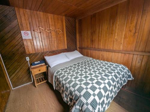 a small bedroom with a bed in a wooden room at LA TRANQUILIDAD in Mindo