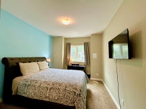 a bedroom with a bed and a flat screen tv at Downtown Whitehorse Deluxe 2 Bedroom Condo in Whitehorse