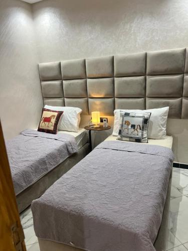 a room with two beds and a large headboard at Very nice modern air-conditioned apartment in Fez in Fès