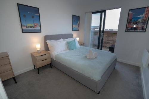a bedroom with a bed with a night stand and a window at Luxury 2 Bed Penthouse Manchester Large Balcony in Manchester